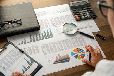 business analysis - calculator, sheet, graphs (business report) and analyst hand, top view