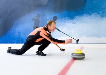 curling player delivering a stone on a curling rink, sliding over the ice