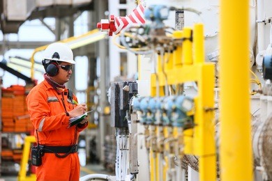 operator or worker recording operation data of oil and gas process at production plant, offshore oil and gas industry in the sea or gulf, operator monitor production process and routine daily record.