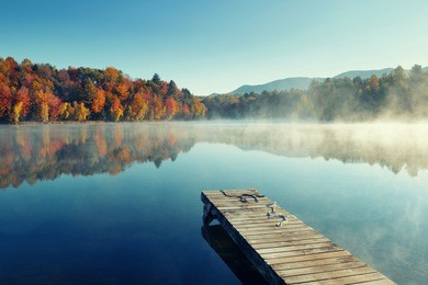 autumn foliage and fog lake in morning with boat dock