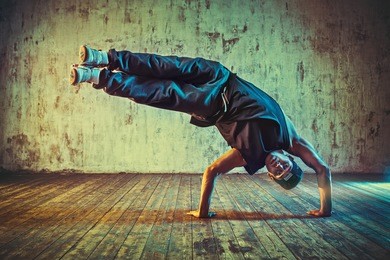 young man break dancing on wall background. blue and yellow vibrant colors tint.