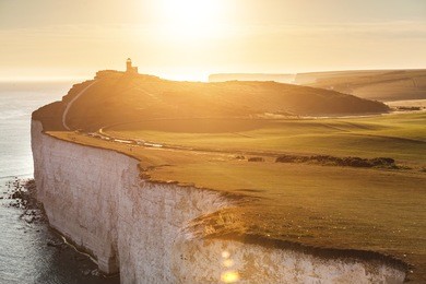 panoramic view of seven sisters cliffs with lighthouse and sea on background at sunset. photo taken from beachy head, on eastbourne side, with backlight sunset. travel and nature concepts.