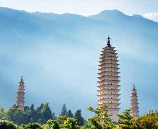 the three pagodas of chongsheng temple in dali, yunnan province, china. scenic mountains are visible in background. ancient pagodas are a popular tourist destination of asia.
