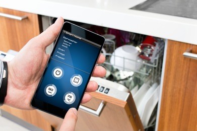 man turns on the dishwasher by smartphone application.