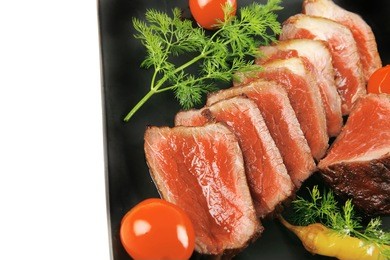 sliced meat on dark plate with vegetables