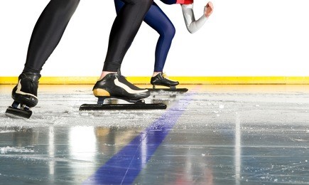 two female speed skaters taking starting positions on the ice behind the starting line