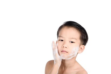 young boy put foam on his face before shaving in the bathroom.
