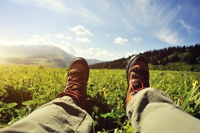 hiker sitting on a grass mountain top with first person perspective view