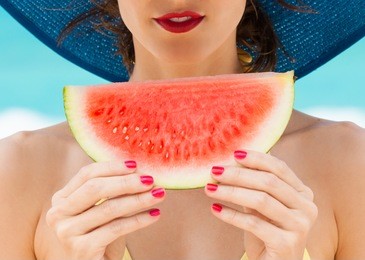 young woman holding slice of watermelon on the beach. colorful summer beach concept.  