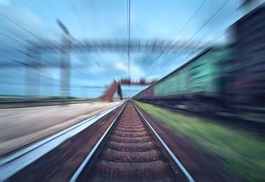 railway station with cargo wagons in motion at sunset. railroad with motion blur effect. railway platform at dusk. heavy industry. conceptual background