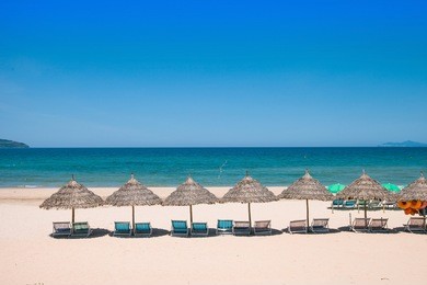 beach umbrellas and deck chairs in front of the my khe beach in da nang, vietnam