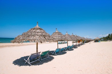 beach umbrellas and deck chairs in front of the my khe beach in da nang, vietnam
