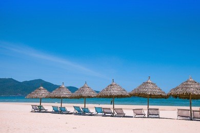 beach umbrellas and deck chairs in front of the my khe beach in da nang, vietnam