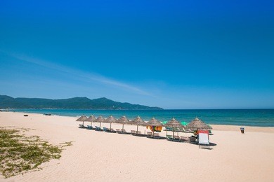 beach umbrellas and deck chairs in front of the my khe beach in da nang, vietnam