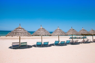 beach umbrellas and deck chairs in front of the my khe beach in da nang, vietnam