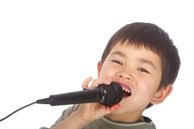 cute young asian boy singing into a microphone isolated on a white background