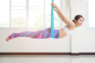 young woman posing doing aerial yoga exercise. 
