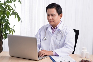 asian doctor typing and using his computer in the office