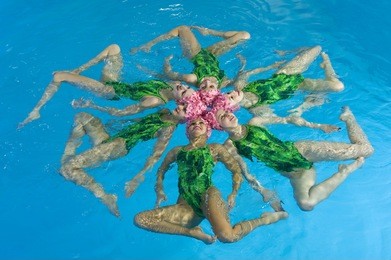 synchronized swimmers hold pose for camera