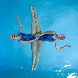 synchronized swimmers hold pose for camera