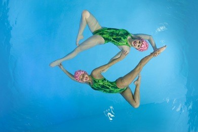 synchronized swimmers hold pose for camera