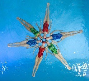 synchronized swimmers hold pose for camera