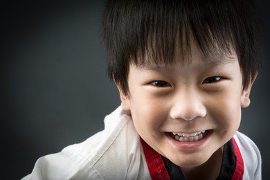 close up of asian cute child training in taekhondo uniform on gray background