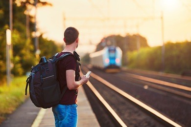 traveler is late at the train station. young man with backpack missed the train and waiting for next.