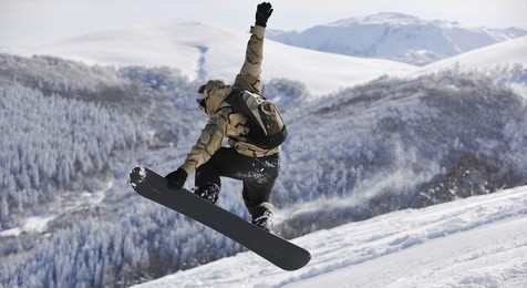 freestyle snowboarder jump and ride free style  at sunny winter day on mountain