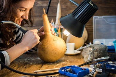 young woman skilled artisan in workshop working with hand tools