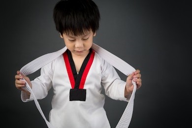 asian cute child training in taekhondo uniform on gray background