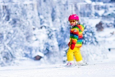 child skiing in mountains. active toddler kid with safety helmet, goggles and poles. ski race for young children. winter sport for family. kids ski lesson in alpine school. little skier racing in snow