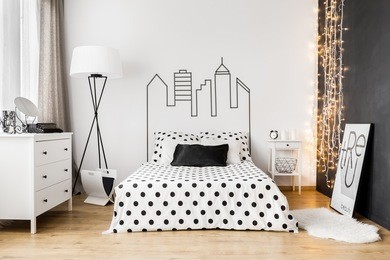 bright bedroom interior with wide bed, commode and one black wall