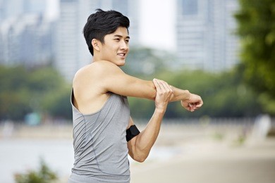 young asian man warming up by stretching arms before exercise.