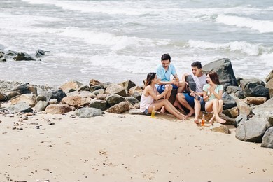 group of friends sitting on beach and singing songs