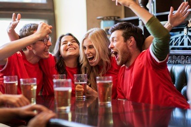 sport, people, leisure, friendship and entertainment concept - happy football fans or friends drinking beer and celebrating victory at bar or pub