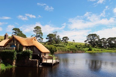 a watermill by the lake with background of beautiful blue sky
hobbiton (movie set), new zealand