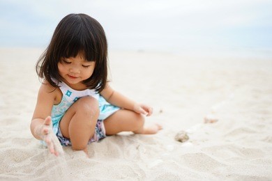 little asian girl playing on beach.
