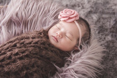 close up portrait of cute little baby girl sleeping comfy on fur blanket