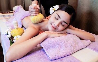 beautiful young girl having massage with herbal balls in spa salon .soft focus