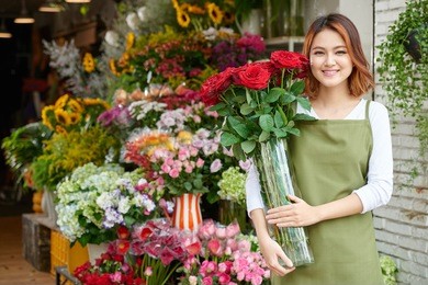 portrait of pretty asian florist with bouquet of roses