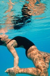 synchronized swimmer performing under water surface