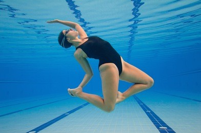 modern dancer performing underwater in a large swimming pool . post processed, grain added