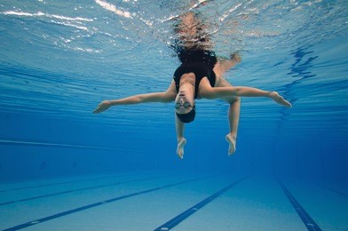 underwater image of a modern dancer performing in a large swimming pool. post processed, grain added. 