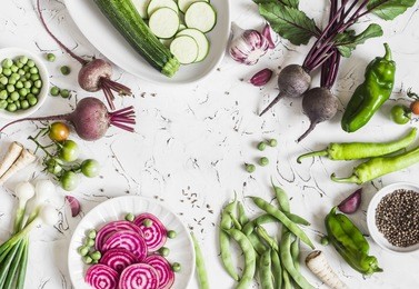 fresh raw vegetables - beets, green peas and beans, zucchini, peppers, onions, garlic, spices on a light background. cooking background, space for text. top view 