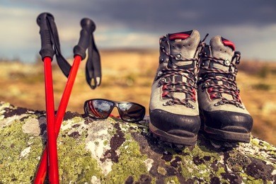 travel outdoor equipment - hiking boots, trekking poles, and sunglasses