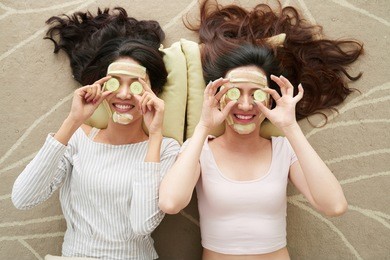 two young women with cucumber masks lying on the floor
