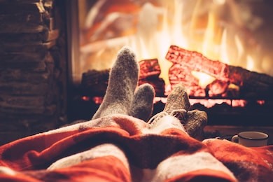 cold fall or winter evening. people resting by the fire with blanket and tea. closeup photo of feet in woolen socks. cozy scene.