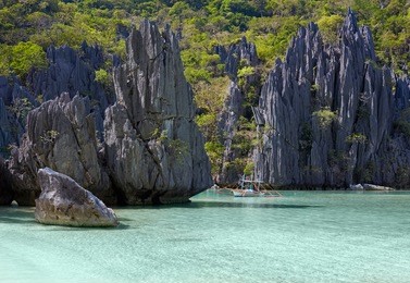 landscape with filippino boat, rocks and blue bay. el nido, palawan island, philippines