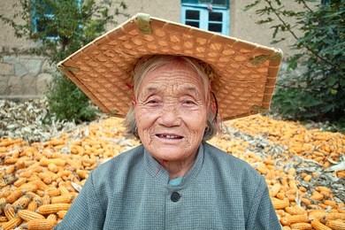 portrait of a old chinese women.she is working in yard of her house.